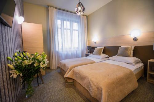 a hotel room with two beds and a vase of flowers at Hotel Kazimierz III in Kraków