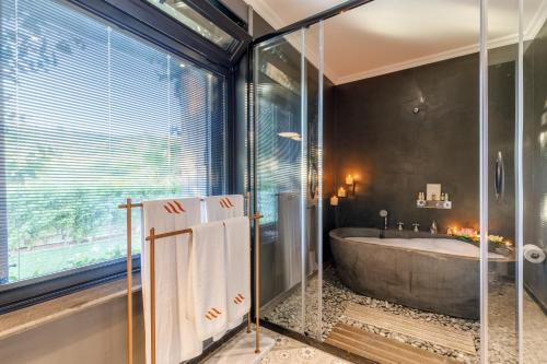 a bathroom with a tub and a large window at Alacatı Port Ladera Hotel - Adult Only in Alaçatı