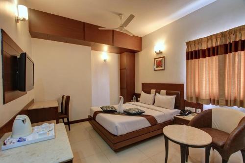 a hotel room with a bed and a table and chairs at Hotel Prince Gardens in Coimbatore
