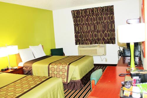 a hotel room with two beds and a desk with a table at Super 8 by Wyndham South Boston VA in South Boston