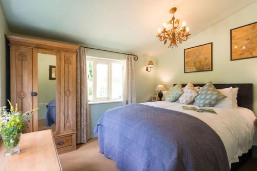 a bedroom with a large bed and a chandelier at Skylarks, enjoy the decking overlooking your garden and wildflower meadow in Old Newton
