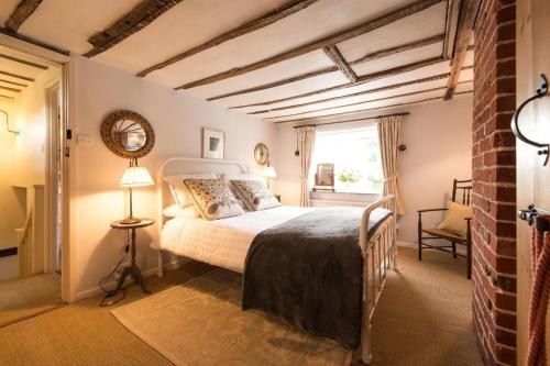 a bedroom with a bed and a window at Spadgers, a flax workers cottage next to fields in a Medieval Village in Long Melford