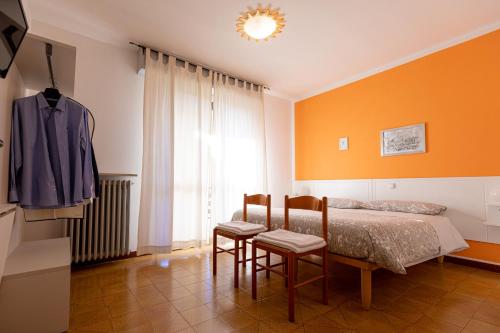a bedroom with orange walls and a bed and two chairs at La Svolta in Chiuro