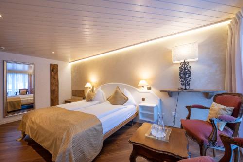 a hotel room with a bed and a chair at Seilers Vintage Hotel & Spa in Kandersteg
