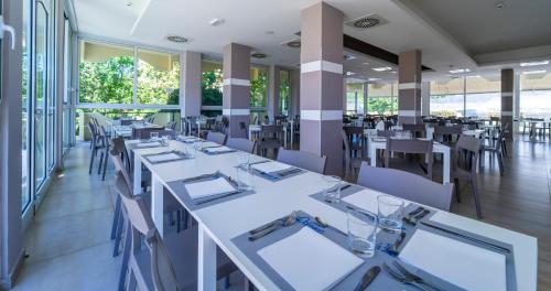 リミニにあるHotel Oceanicの白いテーブルと椅子のあるダイニングルーム