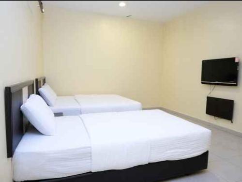a hotel room with two beds and a flat screen tv at The Fern Lodge Hotel in Skudai