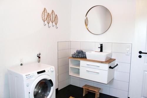 eine Waschküche mit einer Waschmaschine und einem Spiegel in der Unterkunft Ferienhaus Traumblick direkt am See in Weißenstadt