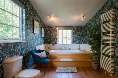 a bathroom with a tub and a chair in it at The Old Steam Mill, luxury, spacious, beautiful grounds, stunning location in Hartest