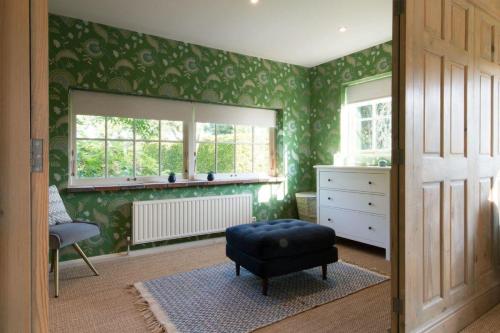 a room with green walls with a ottoman and a window at The Old Steam Mill, luxury, spacious, beautiful grounds, stunning location in Hartest