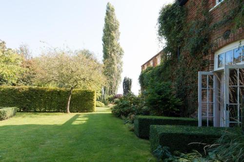 a garden with a house and a yard with green grass at The Old Steam Mill, luxury, spacious, beautiful grounds, stunning location in Hartest