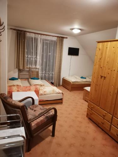 a bedroom with two beds and a chair and a tv at Pod Smrcinou in Nová Pec