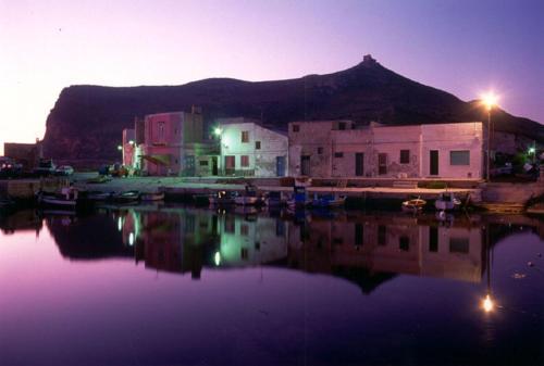 un gruppo di edifici e un porto turistico di notte di Il Cubo, monovano col mare su tre fronti. a Favignana