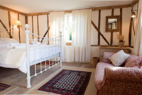 a bedroom with a white bed and a couch at Bromans Barn a beautiful cottage by the Sea and Cudmore Nature Reserve in West Mersea