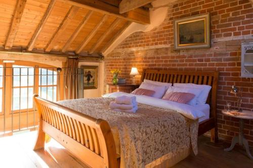 a bedroom with a large bed in a brick wall at Dons Barn a Stunning cottage just a walk across the fields to a great pub 