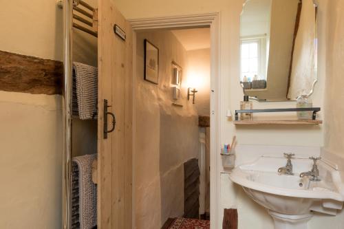 a bathroom with a sink and a mirror at Putts Cottage hidden away at the end of a cart track, happily lost in Sudbury