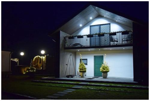 a house with a green door and balcony at night at Krzaczasty Zakątek in Zdziary