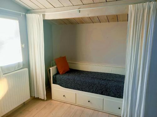 ein kleines Schlafzimmer mit einem Bett mit orangefarbenem Kissen darauf in der Unterkunft Les Jardins de La Palaire - Gîte T2 avec jardin in Cugand