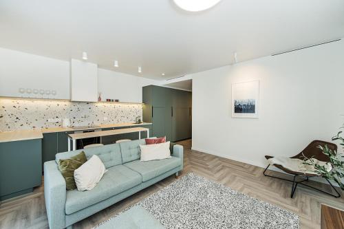 a living room with a blue couch and a kitchen at Cozy Piliamiesčio apartament by URBAN RENT in Kaunas