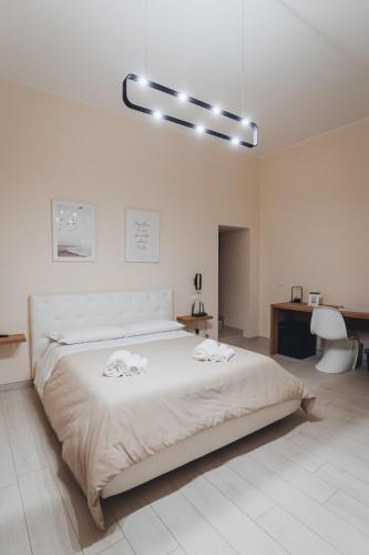 a white bedroom with a large bed and a desk at A-mare Exclusive Rooms & Suites in Taranto