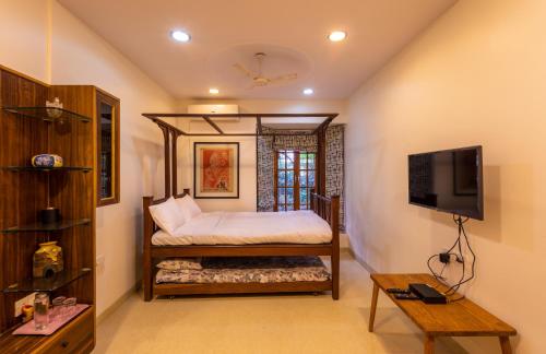 Un dormitorio con una cama y un televisor. en SaffronStays Birdsong, Madh - pet-friendly villa at Madh Island, en Bombay