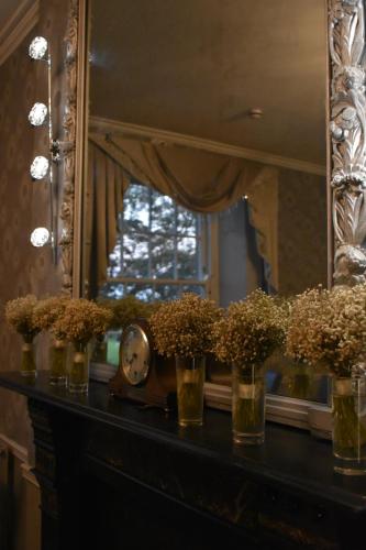 a table with vases of flowers and a mirror at Crug Glas Country House in St. Davids