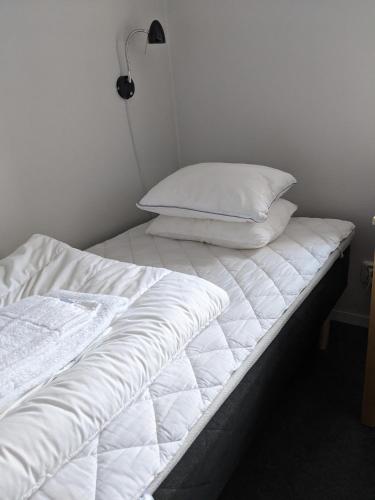 a bed with white sheets and pillows on it at Valla Folkhögskola in Linköping