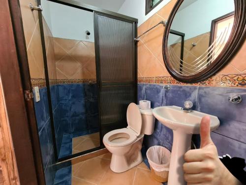 a person giving a thumbs up in a bathroom with a toilet and a mirror at Finca Hotel La Consentida Escondida in San Jerónimo