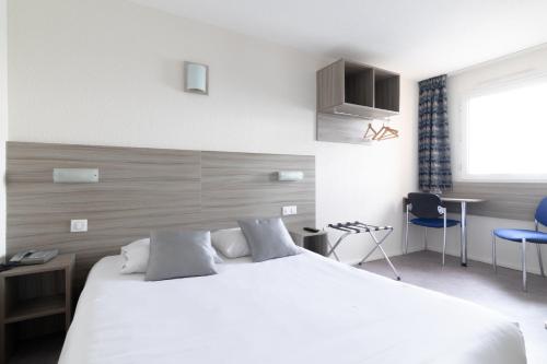 a bedroom with a large white bed and blue chairs at B&B HOTEL Sète Centre Gare in Sète