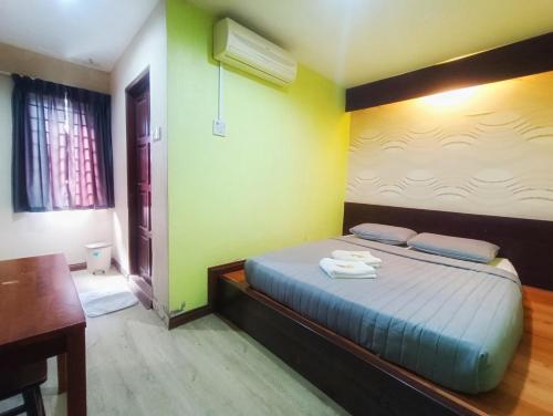 a bedroom with a bed and a desk and a table at Hotel Musfa in Kota Bharu