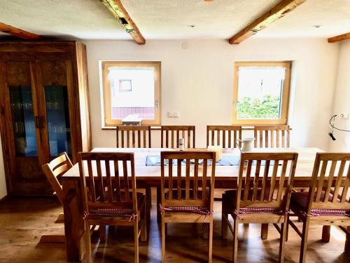 a dining room with a table and chairs and two windows at Landhaus Wiesle in Tannheim