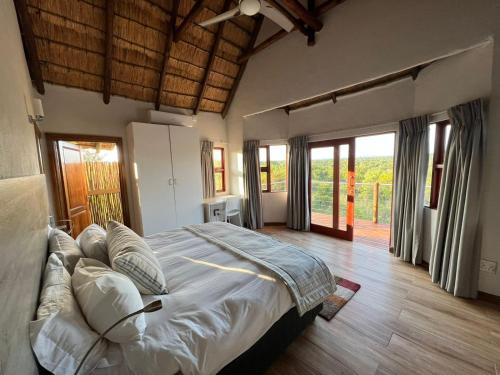 Un dormitorio con una cama grande en una habitación con ventanas. en Nyala View, Mabalingwe, en Mabula