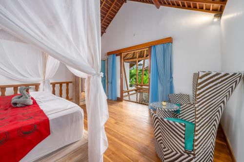 una camera da letto con un letto e una sedia di The Secret Jungle Villas Berawa a Canggu
