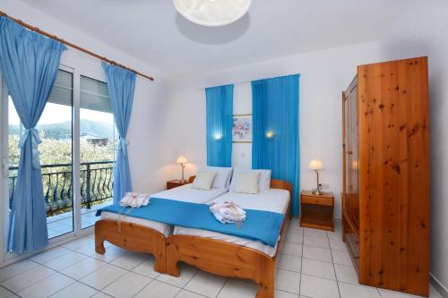 a bedroom with a bed with blue curtains and a balcony at Effi's Garden Villa in Limenas
