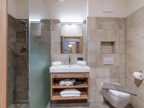 a bathroom with a sink and a toilet and a shower at Isskogel Suites in Gerlos