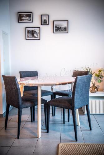 a dining room table with chairs and a white wall at Le Samélie, Superbe appartement Bray-Dunes avec stationnement privatif in Bray-Dunes