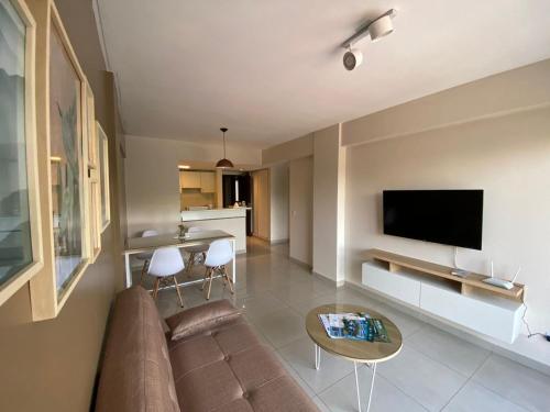 a living room with a couch and a flat screen tv at 9 de Julio Park Suites in San Miguel de Tucumán