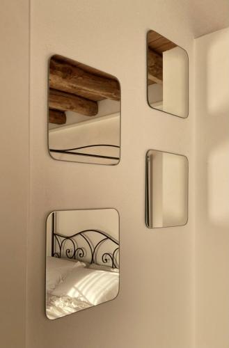 three mirrors on a wall with a bed in a room at Combo Rooms in Garna dʼAlpago