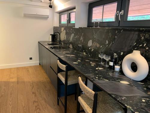 a kitchen with a black counter with chairs and a vase at Sangrita Nida ADULTS ONLY in Nida