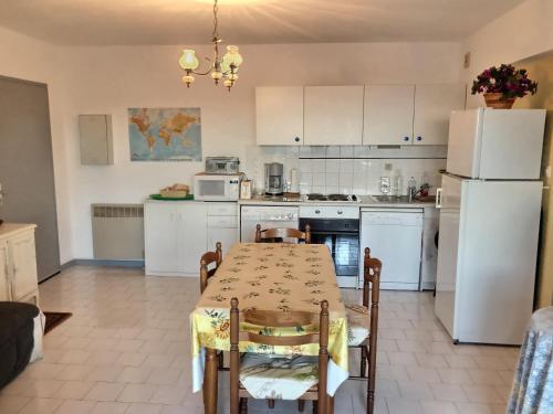- une cuisine avec des appareils blancs, une table et des chaises dans l'établissement Confortable appartement à 700m de la plage de Valras !, à Valras-Plage