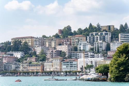 a view of a city from the water with buildings at Hotel Pestalozzi Lugano in Lugano