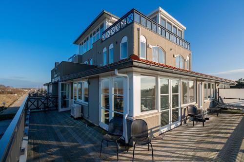 a building with chairs sitting on a deck at Appartment De Strandjutter (4P) - Residence Kabbelaarsbank in Ouddorp