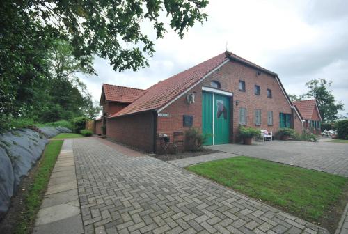 ein Backsteingebäude mit grüner Tür auf einer Straße in der Unterkunft Ferienhaus Eichenhof 35648 in Uplengen