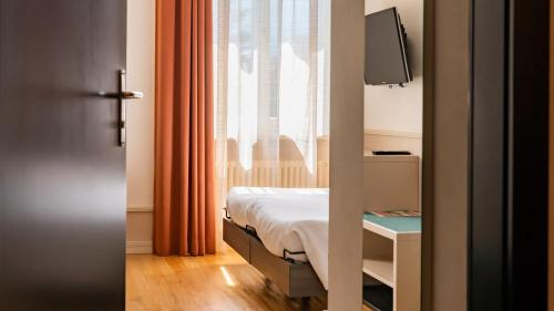 a small bedroom with a bed and a window at Hotel Pestalozzi Lugano in Lugano