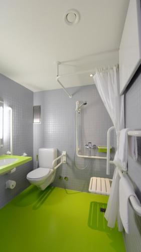 a green bathroom with a toilet and a sink at Hotel Pestalozzi Lugano in Lugano