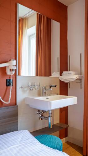 a bathroom with a sink and a mirror at Hotel Pestalozzi Lugano in Lugano