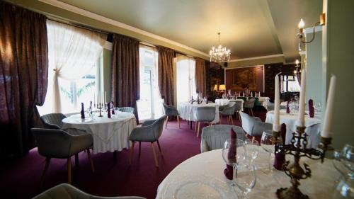 a restaurant with white tables and chairs and windows at Cincis by the Lake in Cinciş