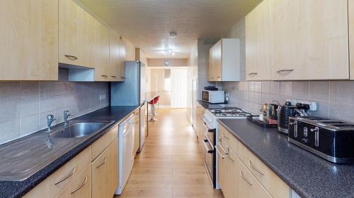 a large kitchen with wooden cabinets and a sink at Orpington North Townhouse in Orpington