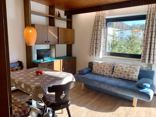 een woonkamer met een blauwe bank en een tafel bij Residence Nordik in Sesto