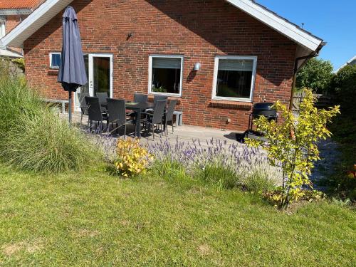 a brick house with a table and an umbrella at Hyggeligt byhus ved glasværkstedet på Nordmors in Sejerslev