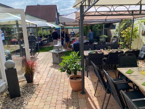a patio with tables and chairs and people sitting at tables at Hotel Ebnet in Mutterstadt